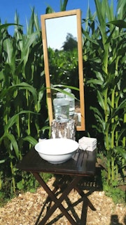 The lavabo is right by the corn bed and the beautiful wooden toilet is close by.
